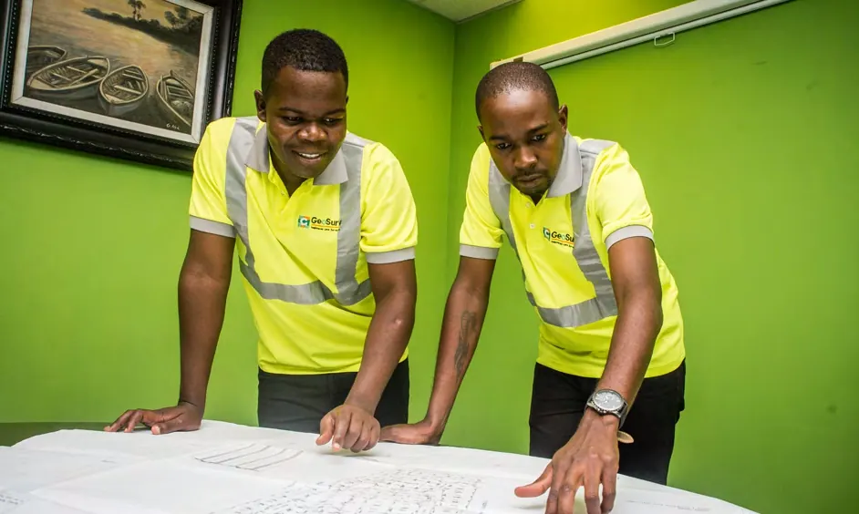 Two GeoSurv surveyors reviewing survey plans